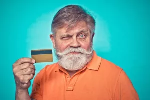 senior man holds credit card and winks